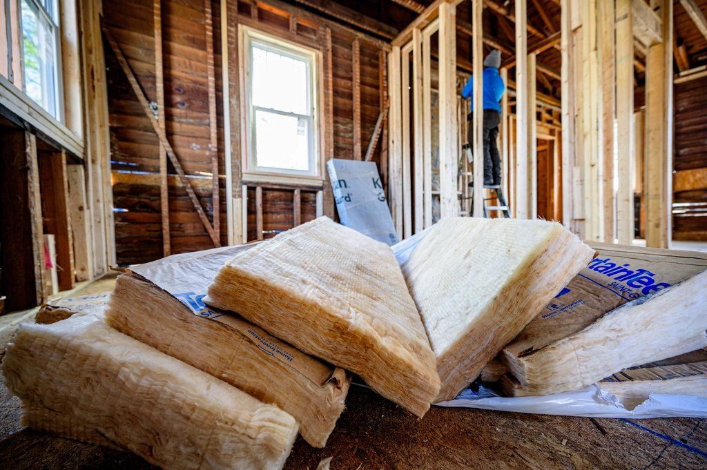 Wood-framed interior with batts of fibreglass insulation stacked on the floor