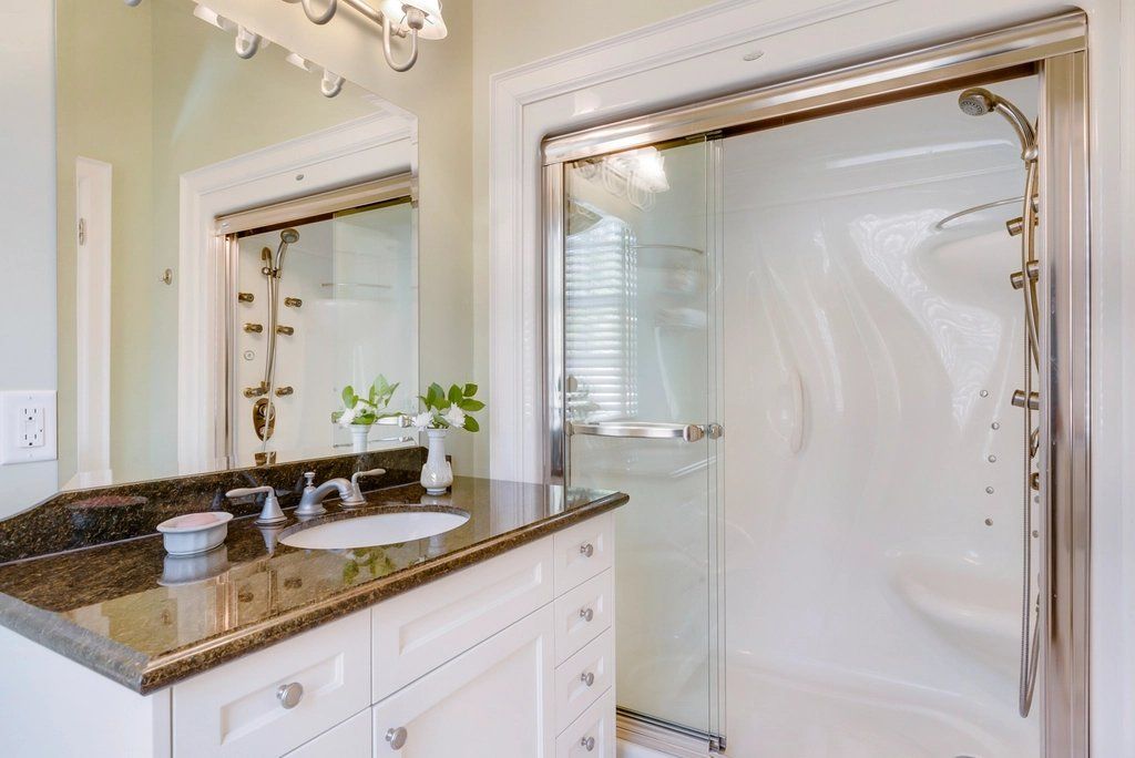 Bathroom with granite-top vanity, white cabinet and glass shower enclosure