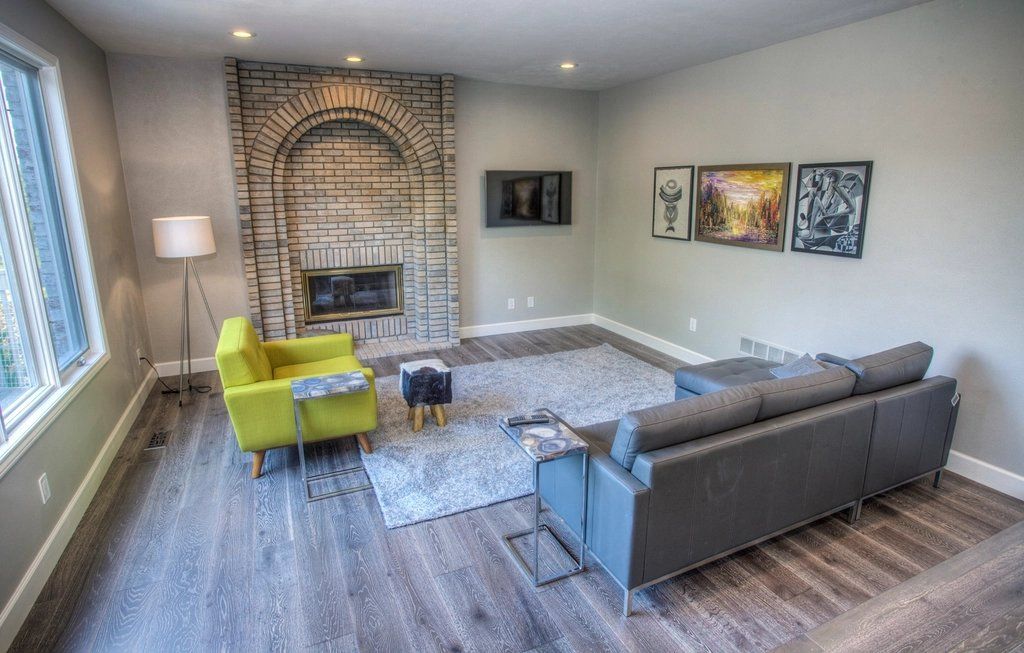 Living room with grey wood-plank floor, sofa and brick fireplace