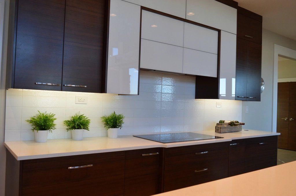 Kitchen counter with under-cabinet lighting, white tile backsplash and potted herbs